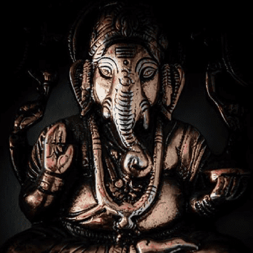 Bronze statue of Lord Ganesha, depicted seated with raised hand and traditional ornaments, symbolizing wisdom and prosperity in Hindu culture.